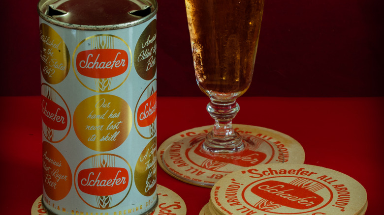 Old can of Schaefer beer poured out in a glass, on a coaster