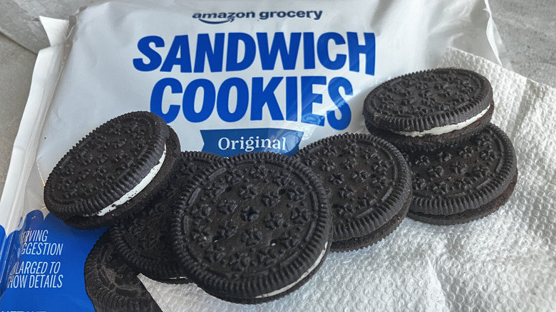 A close-up shot of the sides and tops of Amazon Grocery chocolate sandwich cookies lined up along the edge of a  white package