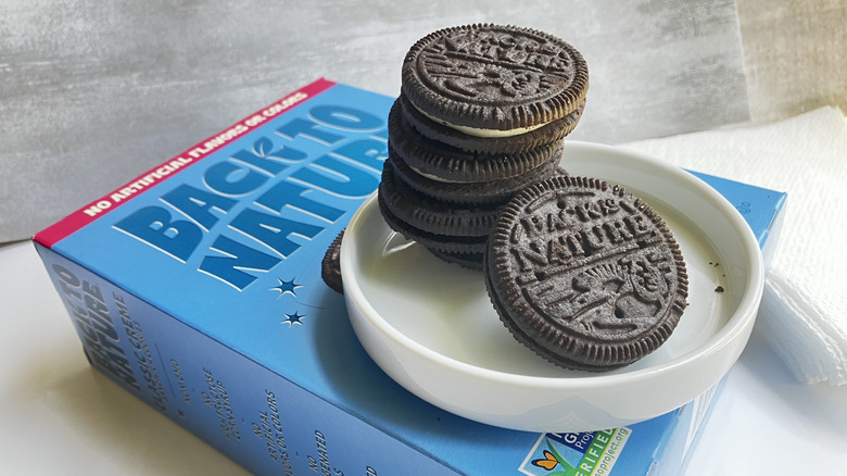 A close up shot of Back to Nature chocolate sandwich cookies piled in a small white dish on top of a blue cookie box.