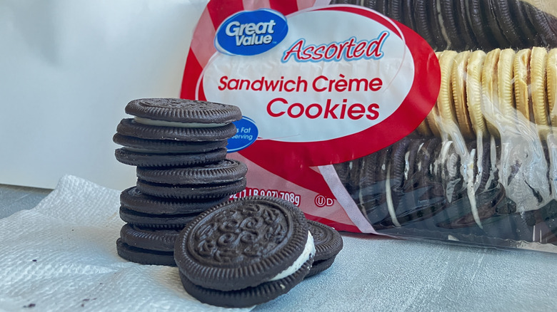 Great Value chocolate sandwich cookies stacked in front of a package of assorted sandwich creme cookies.
