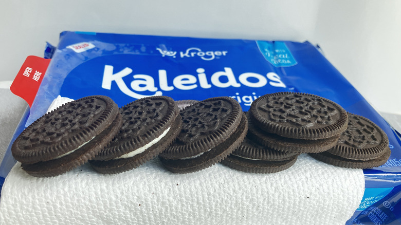 A close-up shot of the sides and tops of Kroger Kaleidos chocolate sandwich cookies lined up along the edge of a blue and white package