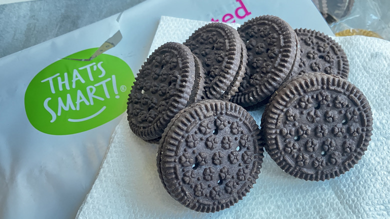 A close up of That's Smart flower-textured chocolate sandwich cookies, with a That's Smart logo in the background.