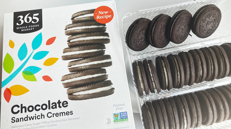 A box of Whole Foods 365 Chocolate Sandwich Creme cookies next to a tray of chocolate sandwich cookies.