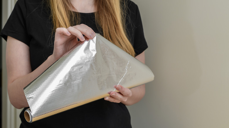 Woman holding roll of aluminum foil