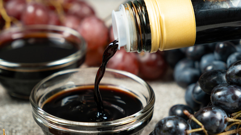 Balsamic vinegar pouring from a bottle into a glass bowl