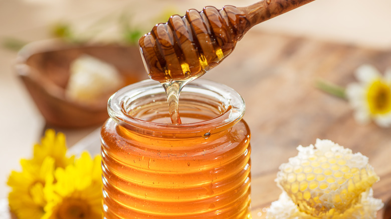 A honey dripper over a jar of honey