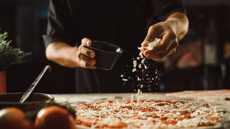 The hands of a chef preparing a pizza