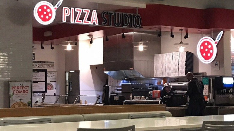 A customer ordering at the counter of a Pizza Studio