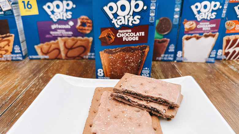 Frosted chocolate fudge Pop-Tart cut on a plate with package in background