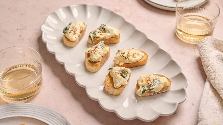 Spinach artichoke dip crostini on a scalloped white plate