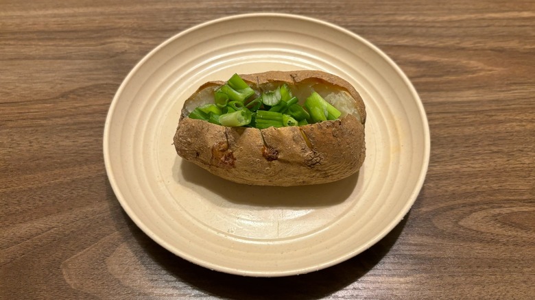 baked potato with green onion on plate