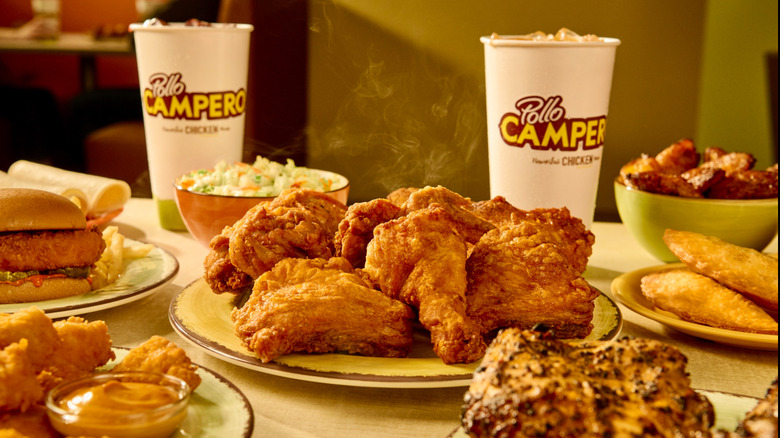 a table filled with Pollo Campero chicken, sides, and drinks
