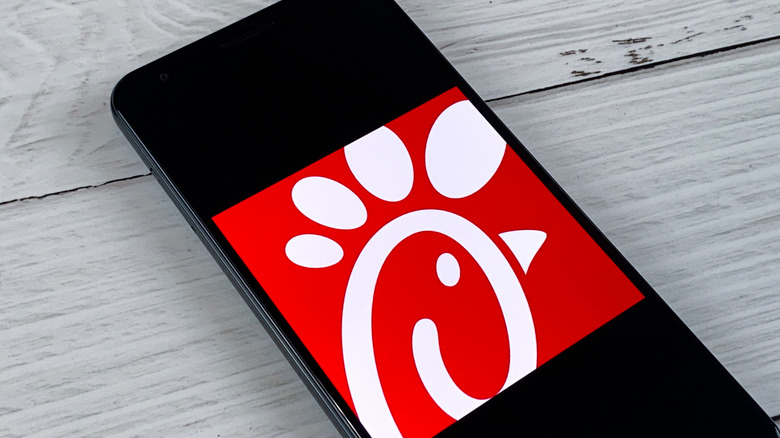 A black phone lying on a wooden surface, displaying the Chick-fil-A logo.