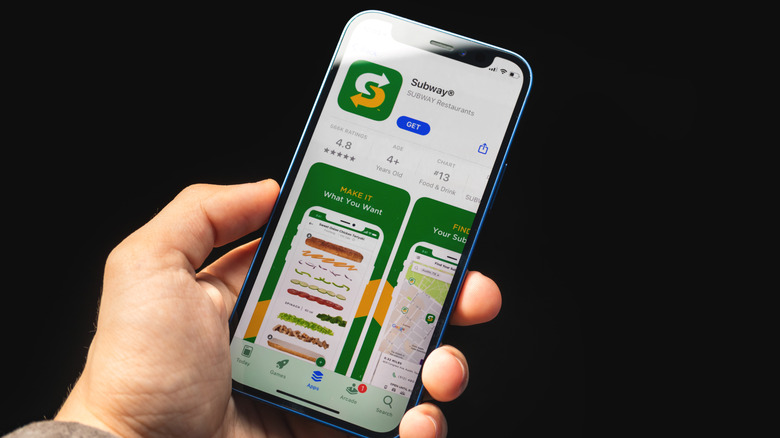A person holding a phone displaying the Subway app