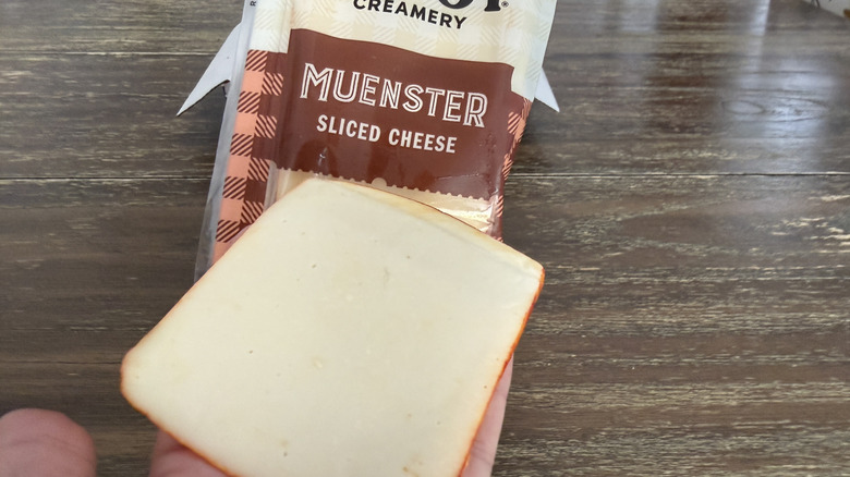 Hand holding a slice of Cabot Muenster cheese
