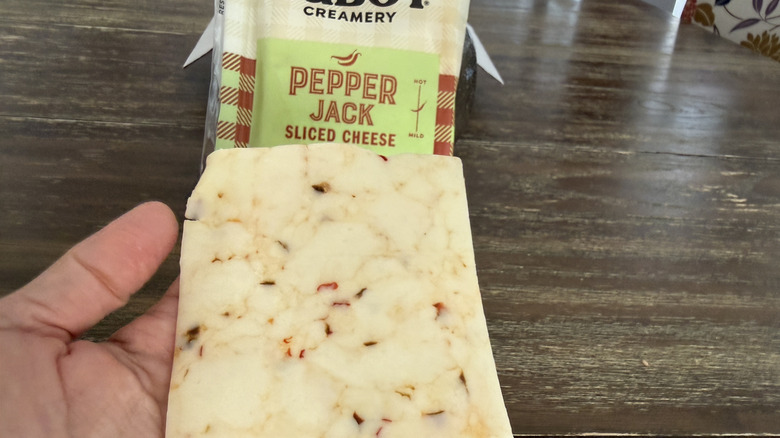 Hand holding a slice of Cabot Pepper Jack Sliced Cheese