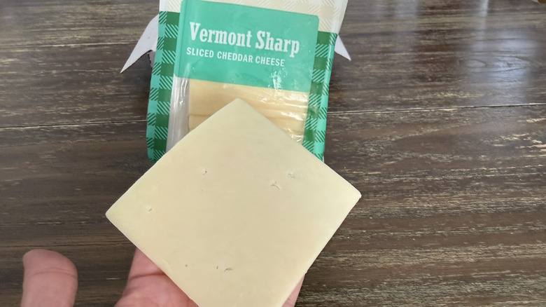 Hand holding a slice of Cabot Vermont Sharp Cheddar Cheese