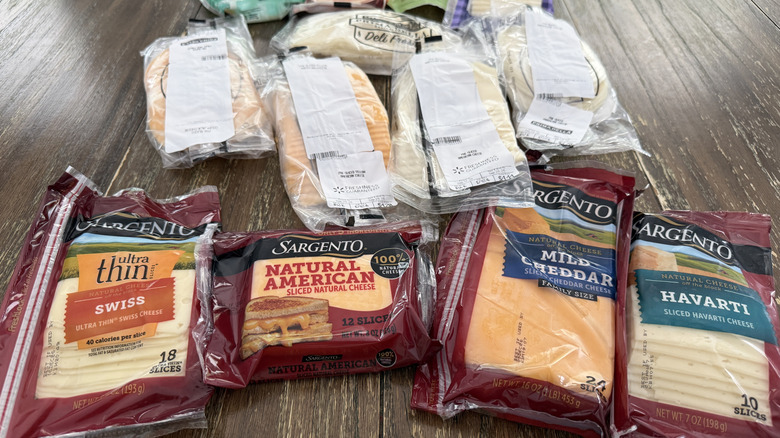 An assortment of sliced cheeses on a wooden table