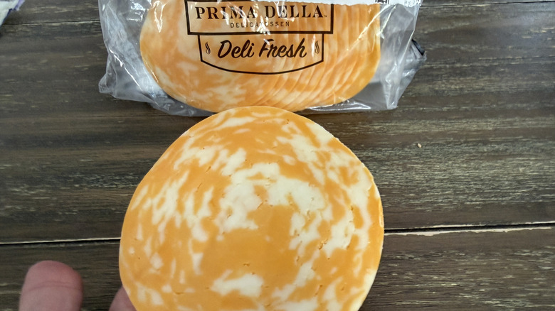 Hand holding a slice of Prima Della Colby Jack