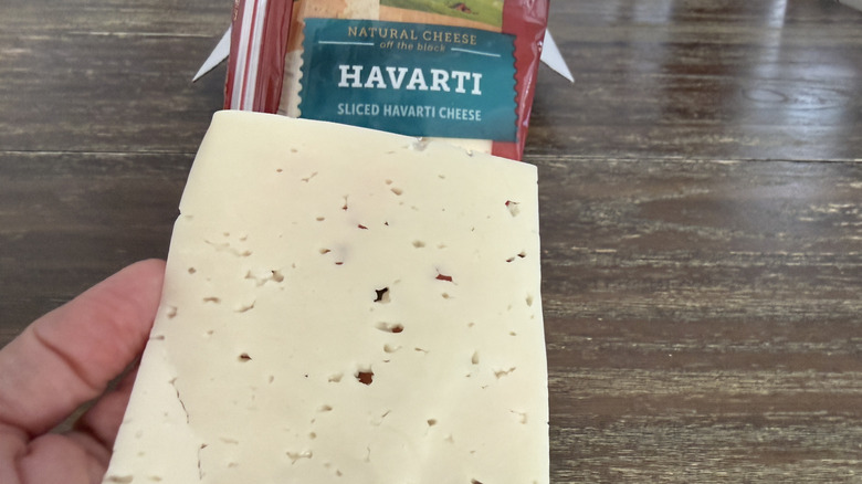 Hand holding a slice of Sargento Havarti cheese