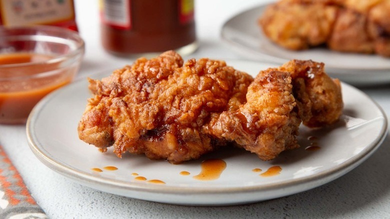 Fried hot honey mustard chicken on a white plate drizzled with sauce