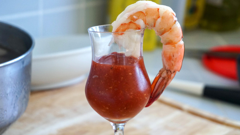 A shrimp cocktail served on a small glass of cocktail sauce