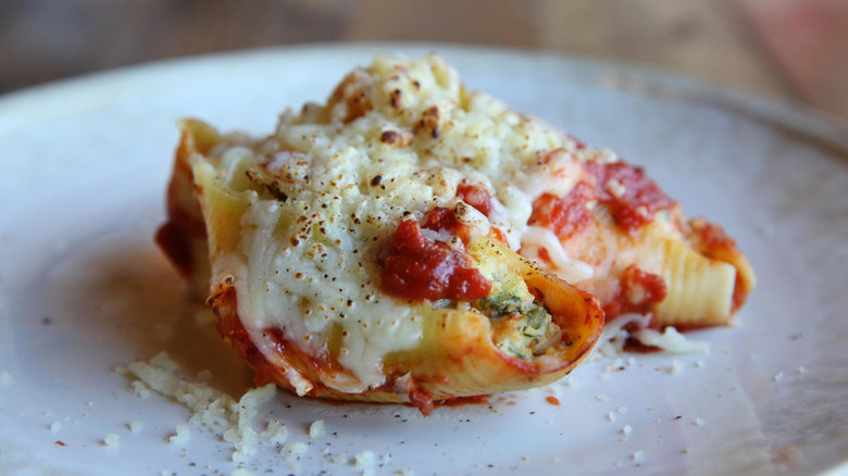 A single serving of stuffed shells featuring two pasta shells filled and topped with cheese and sauce