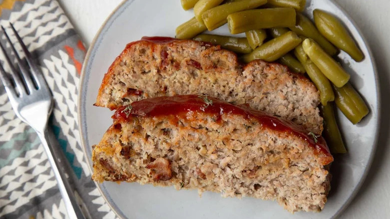 Slices of homemade meatloaf on a plate with green beans