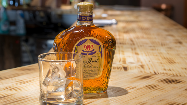 A bottle of Crown Royal whiskey next to a glass