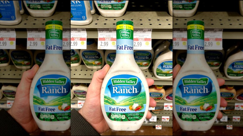 A hand holding Hidden Valley ranch dressing inside a supermarket, mirrored