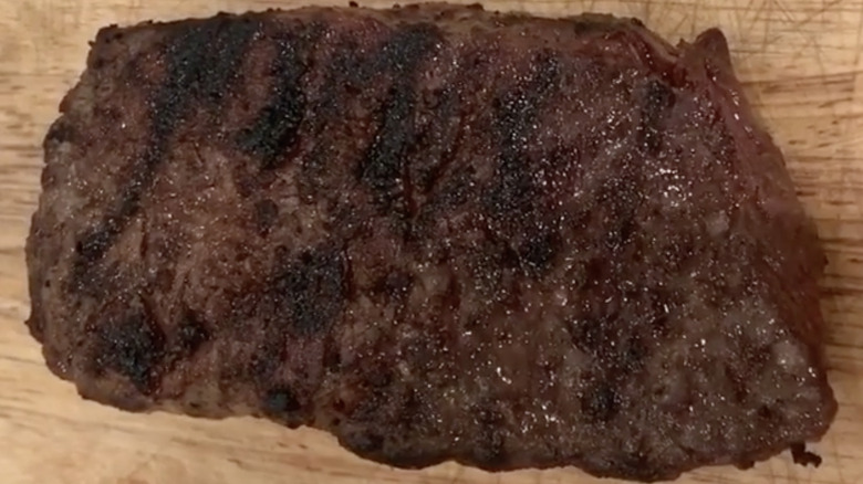 cooked Boston strip steak on wooden board