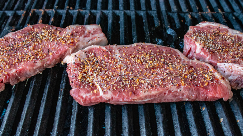 steaks on grill covered in Montreal seasoning