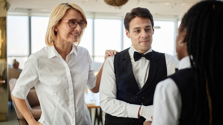 Woman resting hand on waiter's shoulder