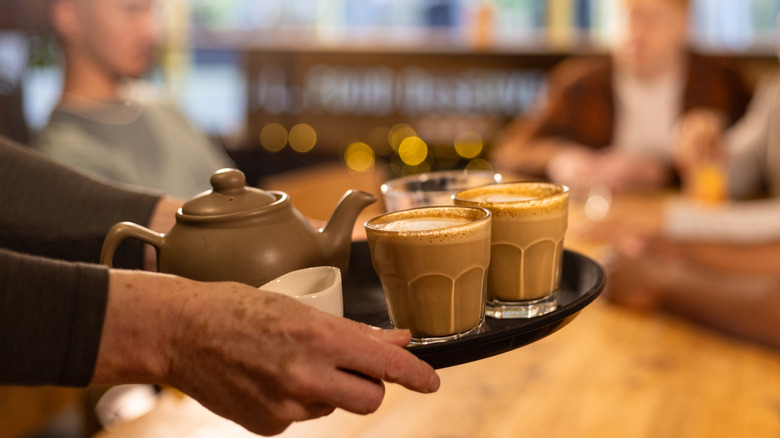 Waiter serving coffee and tea to customers