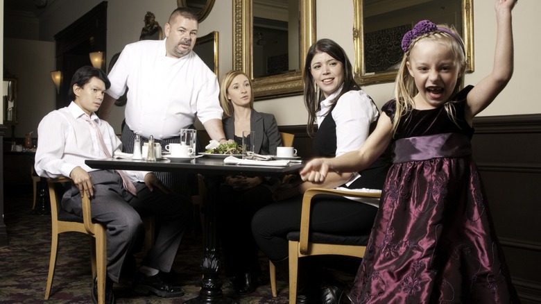 A little girl is acting up in a restaurant while diners look on