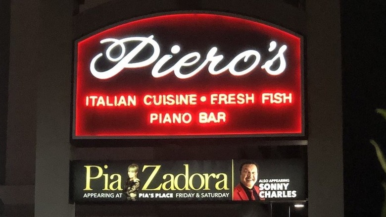 The Piero's sign, lit at night: rectangular with a curved top; outlined in red neon, "Piero's" is in white with "Italian Cuisine, Fresh Fish, Piano Bar" underneath it; ad for Pia Zadora and Sonny Charles appears is in a smaller sign underneath