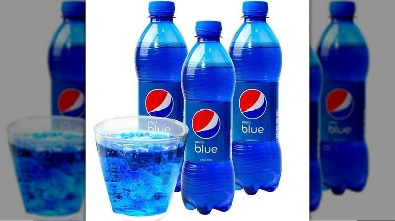 3 Pepsi Blue bottles beside Pepsi Blue in a glass