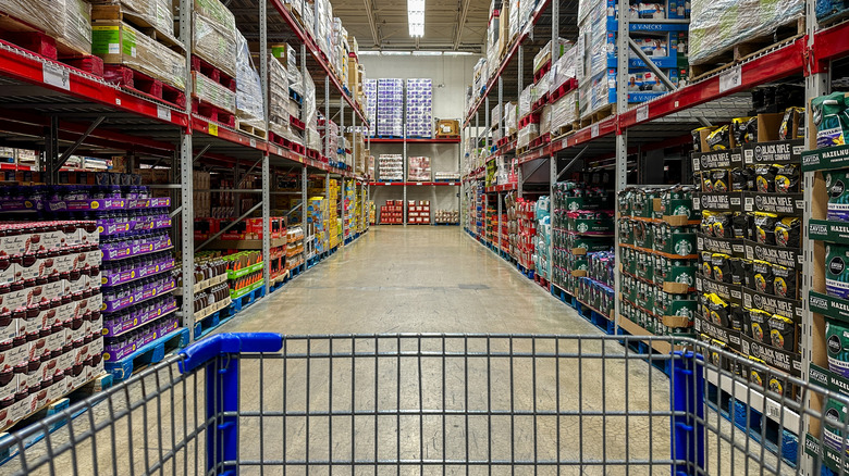 interior of a Sam's Club, aisle of bulk products, the front of a grocery cart in the foreground