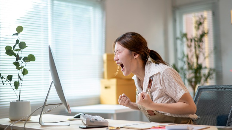 woman clearly annoyed ranting at her computer desk
