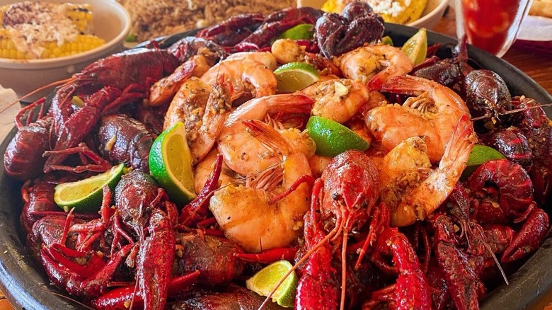 A platter covered with fried shrimp and crawfish surrounded by side dishes.