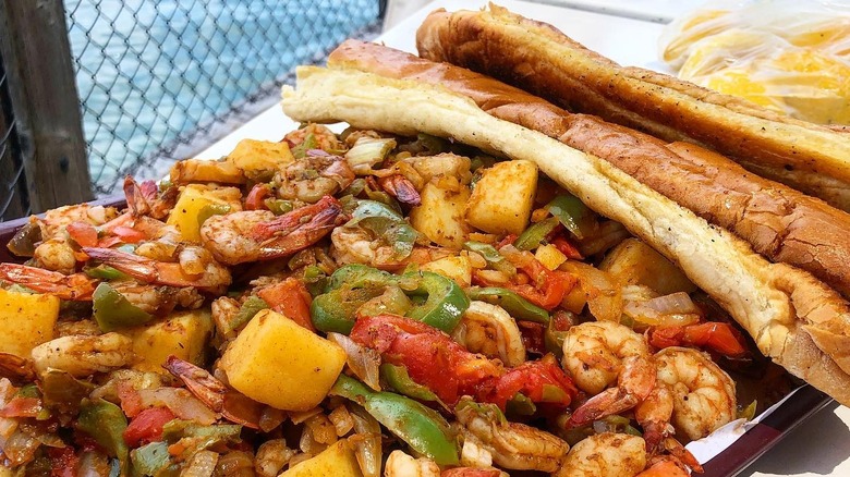A "shrimp tray" from the San Pedro Fish Market, covered in shrimp, peppers, onions, tomatoes and two loves of garlic bread.