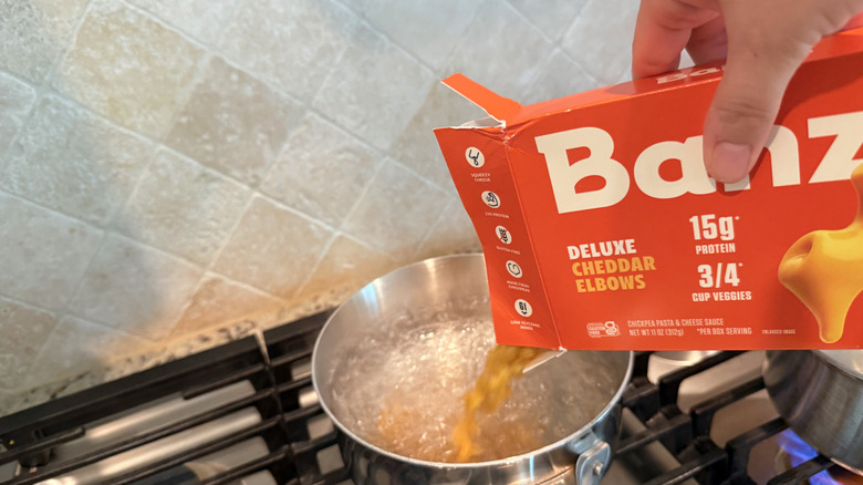Noodles being poured into a pot of hot water