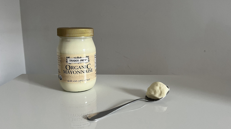 A jar of Trader Joe's Organic mayonnaise with a spoon on a white table