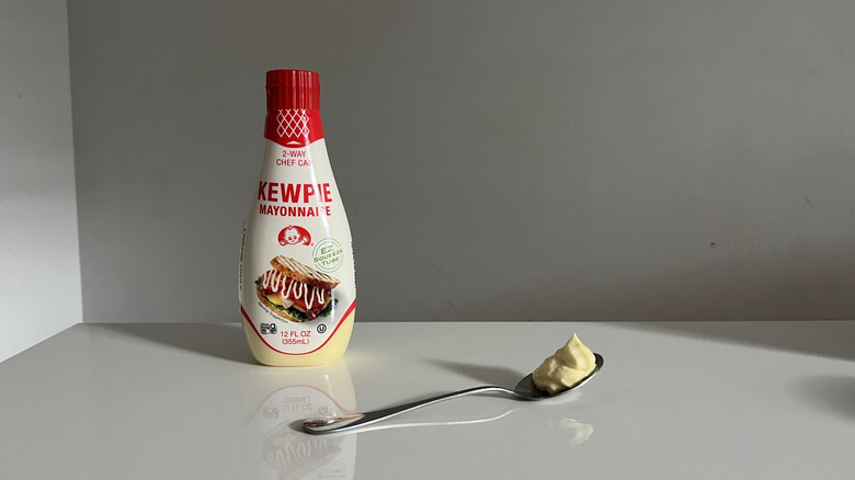 A bottle of Kewpie mayonnaise placed next to a spoon