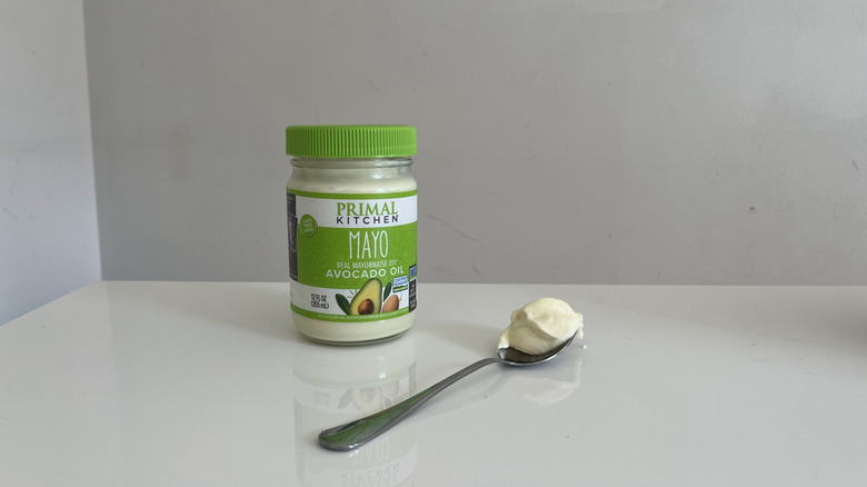 A dollop of Primal Kitchen mayonnaise in a spoon next to a jar