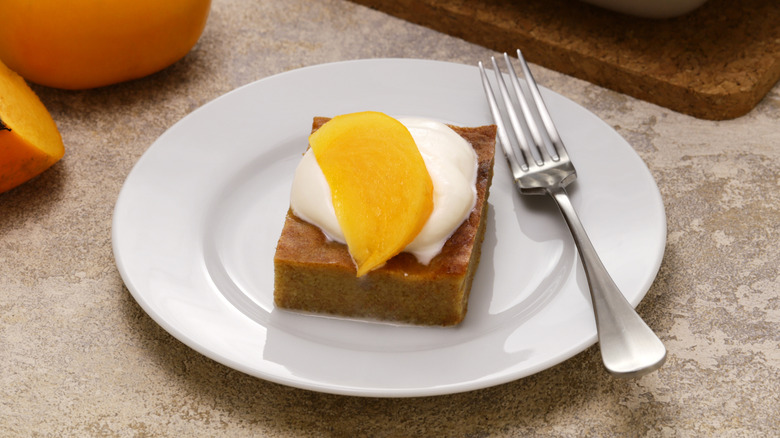 Slice of persimmon pie slice on plate with a slice of persimmon on top and fork