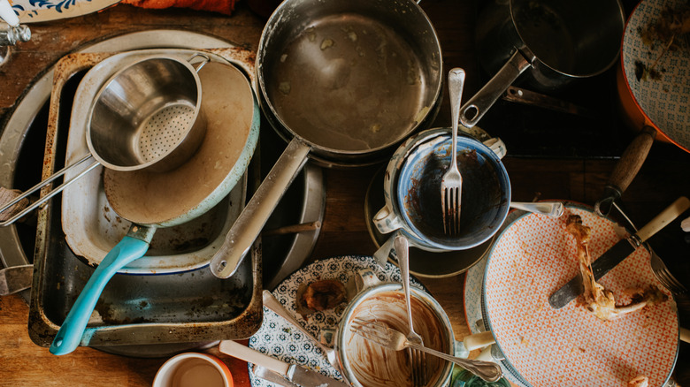 A sink full of dirty pots, pans, dishes, and utensils