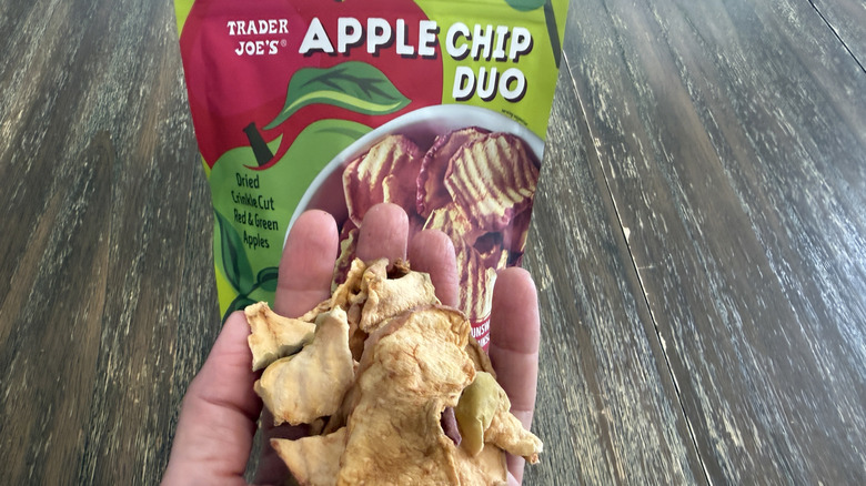 Trader Joe's Apple Chip Duo Chips on wooden table and a handful of them