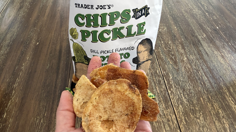 Trader Joe's Chips in a Pickle on wooden table and a handful of them