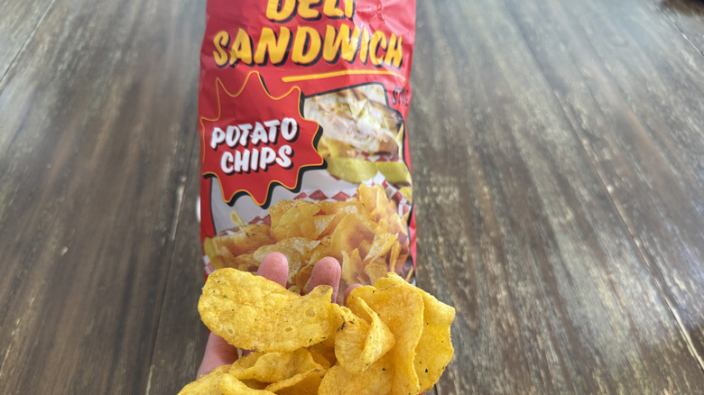 Trader Joe's Deli Sandwich Style Chips on wooden table and a handful of them